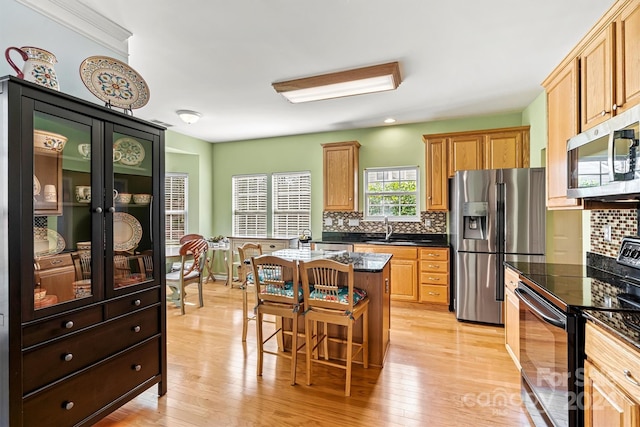 kitchen featuring a kitchen breakfast bar, decorative backsplash, a kitchen island, and appliances with stainless steel finishes