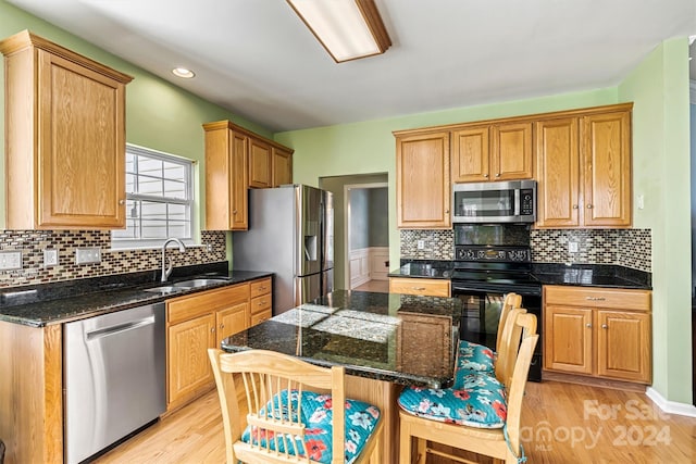 kitchen with a breakfast bar, light wood-type flooring, stainless steel appliances, and sink