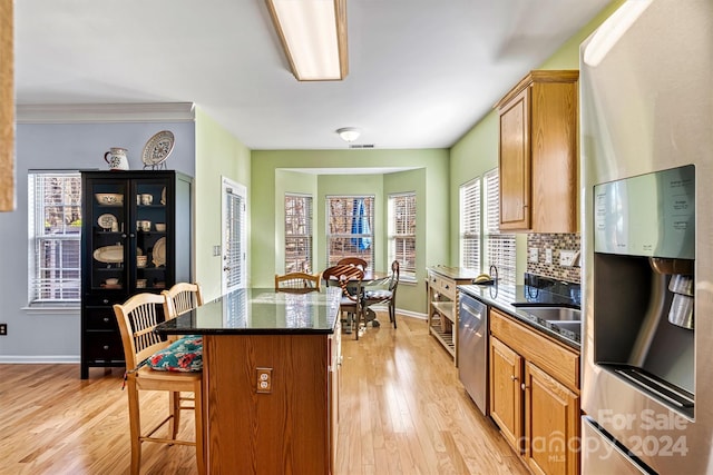 kitchen with light wood-type flooring, backsplash, a breakfast bar, stainless steel appliances, and a kitchen island