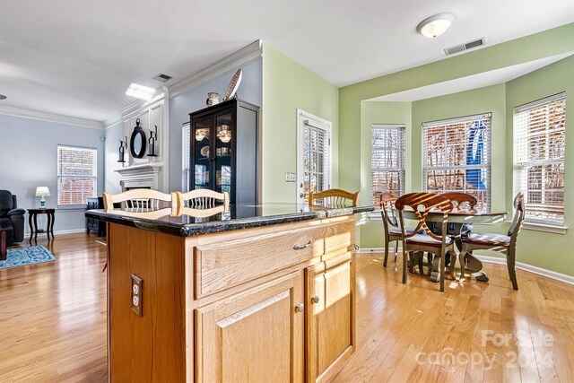 kitchen with crown molding, a center island, a healthy amount of sunlight, and light hardwood / wood-style flooring