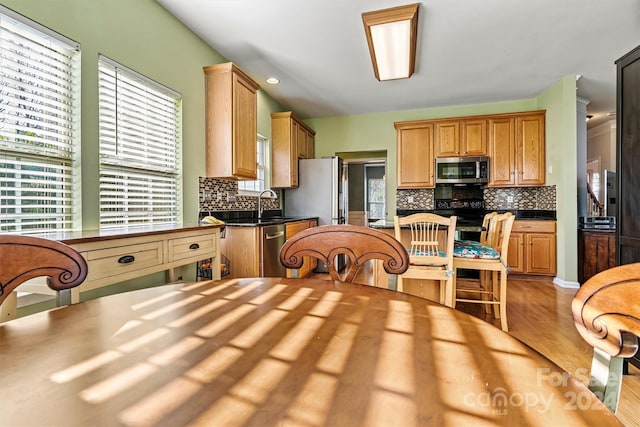 kitchen featuring sink, light wood-type flooring, stainless steel appliances, and tasteful backsplash