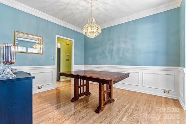 dining area featuring light wood-type flooring, an inviting chandelier, and crown molding