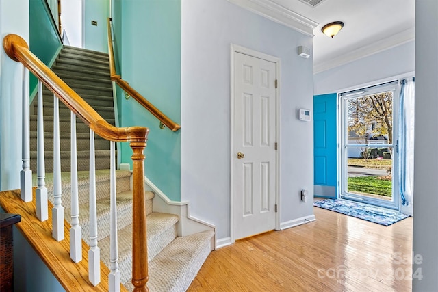 foyer entrance with light wood-type flooring and ornamental molding