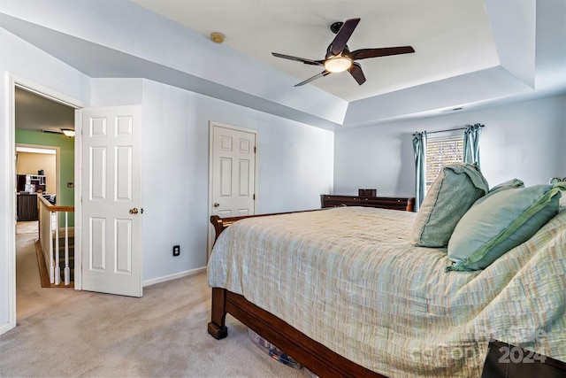 bedroom featuring a tray ceiling, ceiling fan, and light carpet