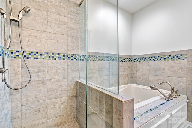 bathroom with shower with separate bathtub and tile walls