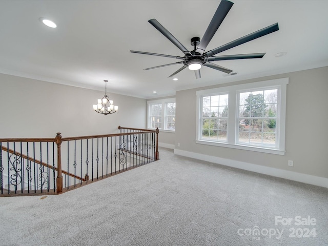 empty room featuring carpet, ceiling fan with notable chandelier, plenty of natural light, and crown molding