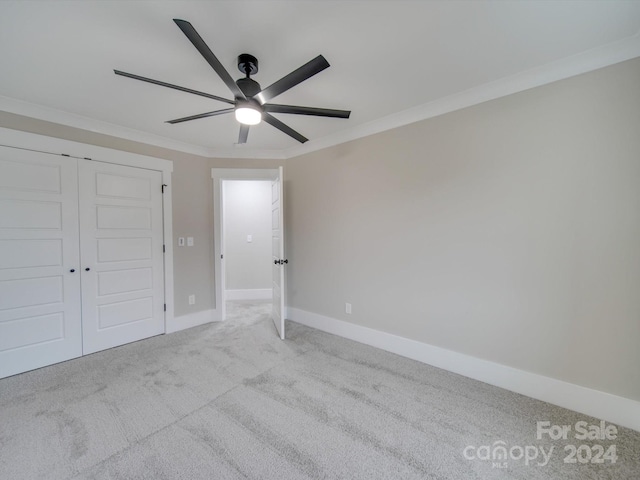 unfurnished bedroom with light carpet, a closet, ceiling fan, and crown molding