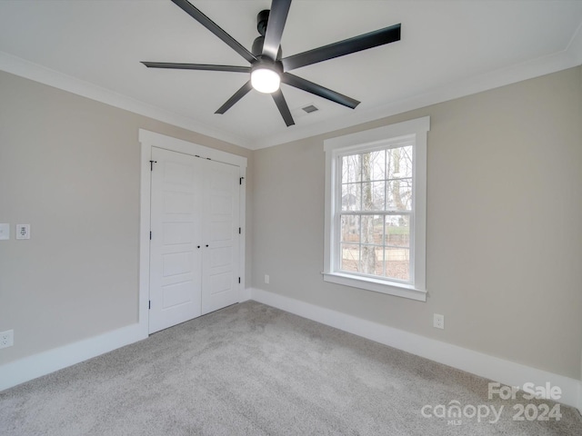 unfurnished bedroom featuring light carpet, a closet, ceiling fan, and ornamental molding