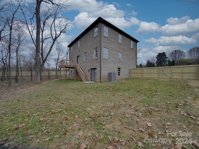 rear view of property featuring a deck, a yard, and central AC