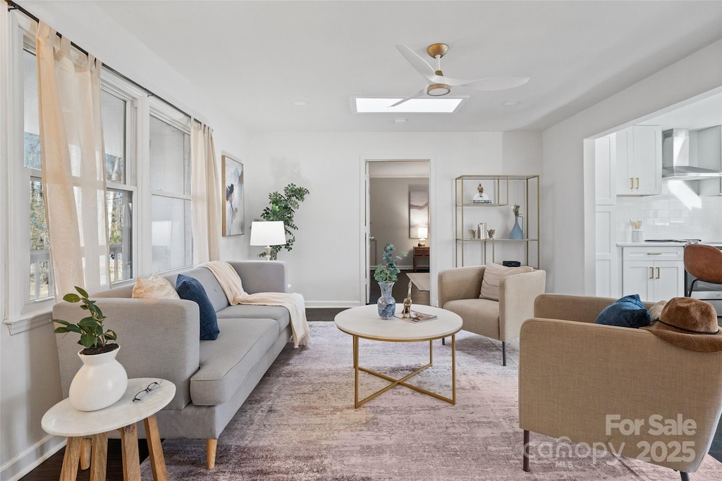 living room with hardwood / wood-style flooring, ceiling fan, and a skylight