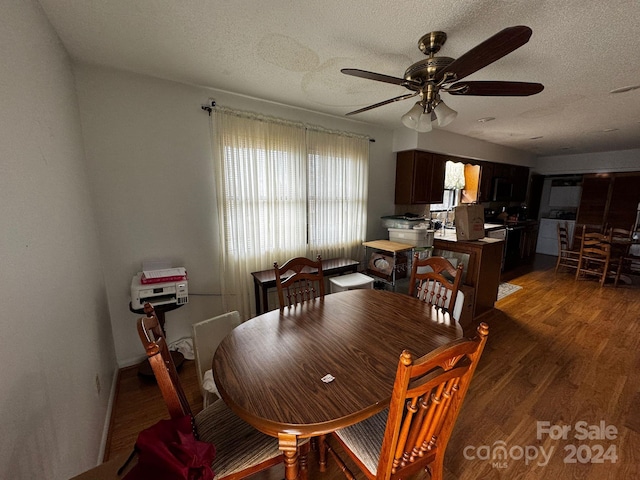 dining space featuring dark hardwood / wood-style floors, a healthy amount of sunlight, a textured ceiling, and ceiling fan