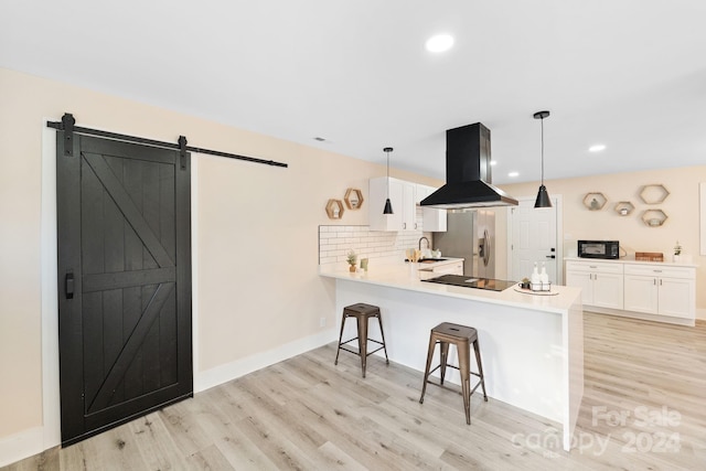 kitchen with a barn door, kitchen peninsula, hanging light fixtures, and island range hood