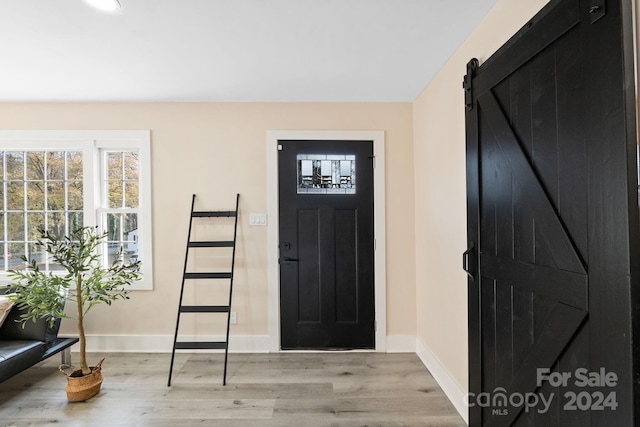 entryway with a barn door and light hardwood / wood-style flooring