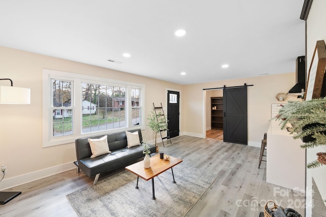 living room with a barn door and light hardwood / wood-style flooring