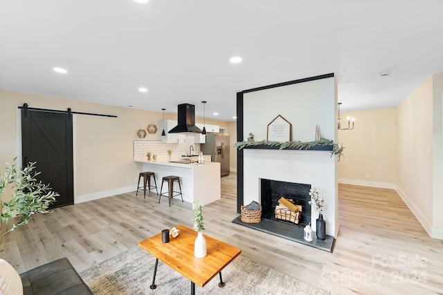 living room featuring light wood-type flooring, a barn door, and sink