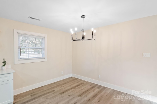 unfurnished dining area featuring light hardwood / wood-style floors and an inviting chandelier