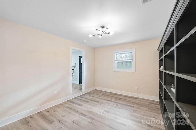 empty room with a notable chandelier and light hardwood / wood-style flooring