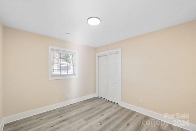 unfurnished bedroom featuring light wood-type flooring and a closet