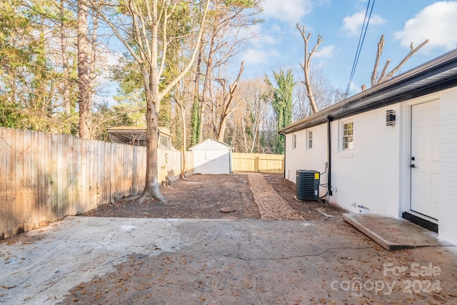 view of yard with central air condition unit, a patio area, and a storage shed