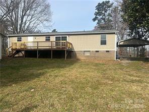 back of property featuring a deck and a lawn