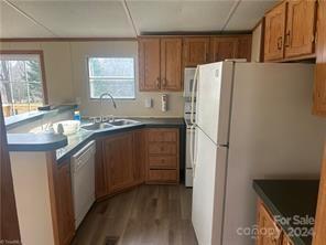 kitchen with a drop ceiling, light wood-type flooring, white appliances, and sink