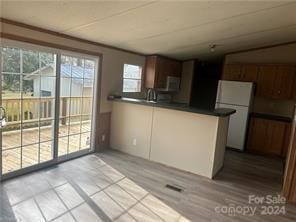 kitchen featuring white fridge, kitchen peninsula, and light hardwood / wood-style flooring