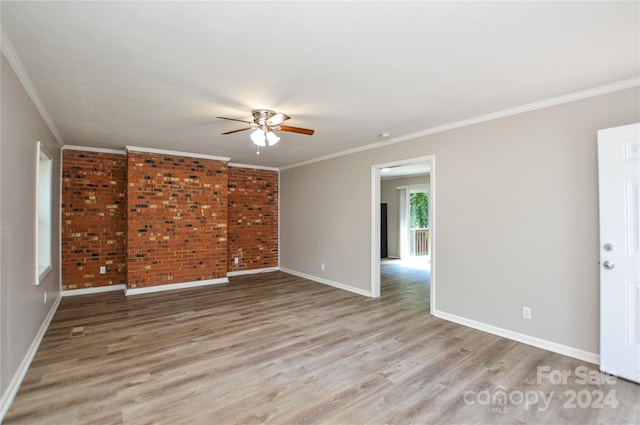 spare room with crown molding, light hardwood / wood-style flooring, and brick wall