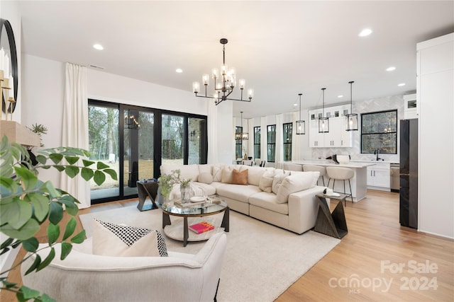 living room with french doors, light hardwood / wood-style flooring, a notable chandelier, and sink