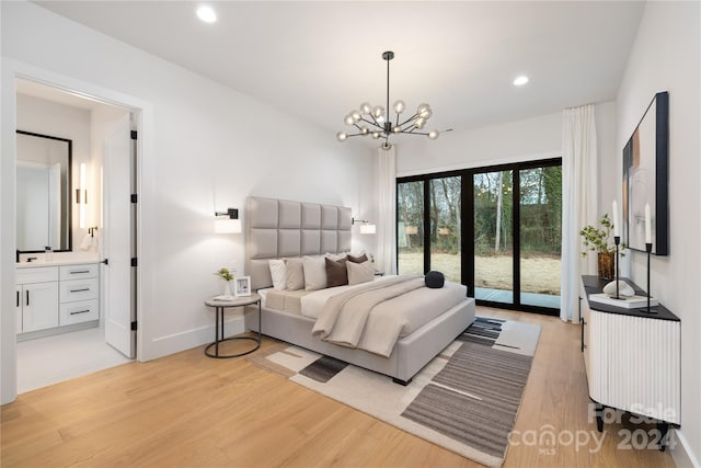 bedroom featuring access to exterior, light hardwood / wood-style flooring, ensuite bath, and an inviting chandelier