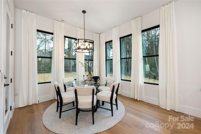 dining area featuring light hardwood / wood-style flooring, a healthy amount of sunlight, and an inviting chandelier