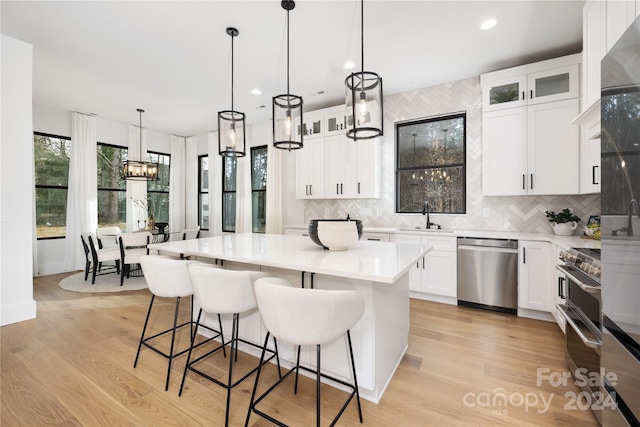 kitchen with a center island, white cabinets, light hardwood / wood-style floors, and appliances with stainless steel finishes