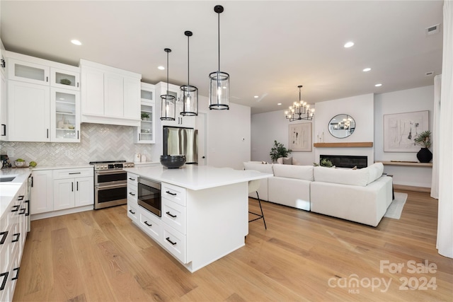 kitchen featuring a kitchen bar, appliances with stainless steel finishes, light wood-type flooring, a center island, and white cabinetry