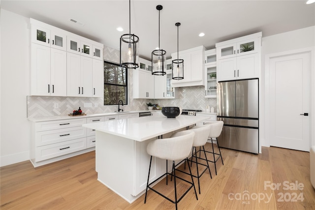 kitchen with appliances with stainless steel finishes, light hardwood / wood-style floors, a kitchen island, and sink