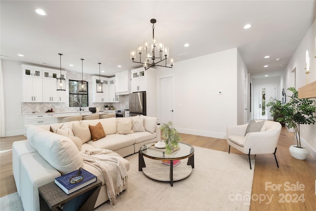 living room with sink, light hardwood / wood-style floors, and a notable chandelier