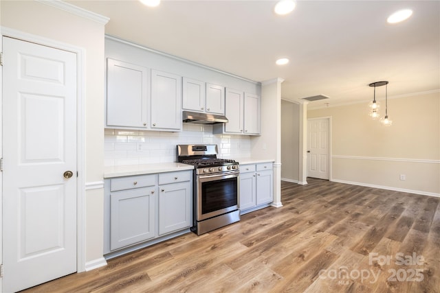 kitchen featuring hanging light fixtures, ornamental molding, stainless steel range with gas cooktop, hardwood / wood-style flooring, and backsplash