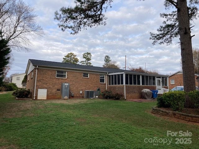 rear view of property featuring central AC, a yard, and a sunroom