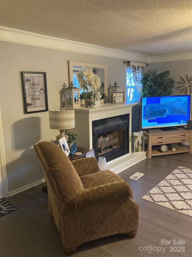 living room featuring a textured ceiling, ornamental molding, and dark hardwood / wood-style floors