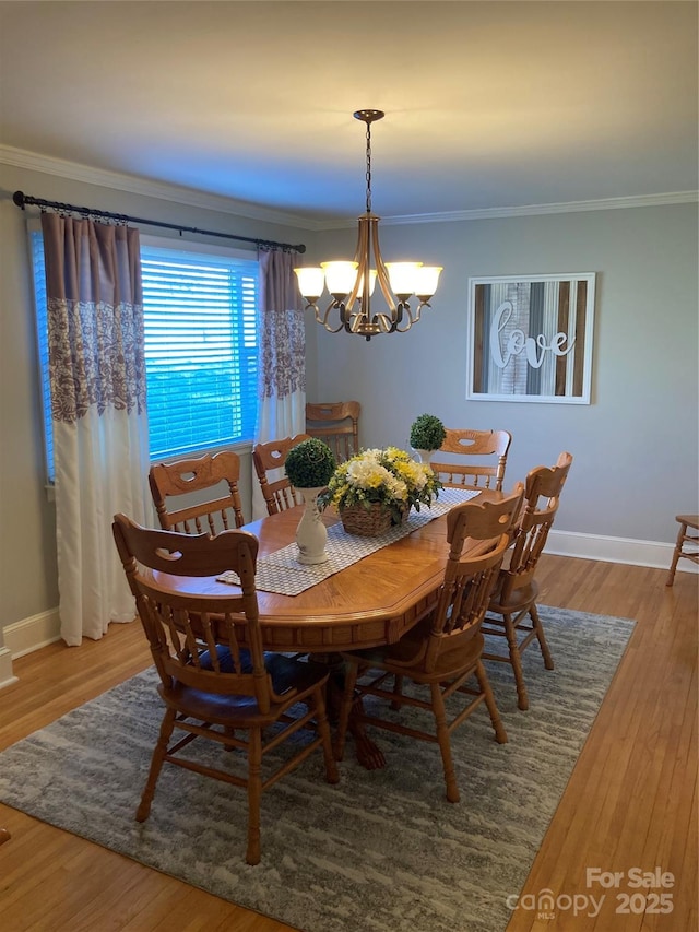 dining space with ornamental molding, a chandelier, and hardwood / wood-style floors