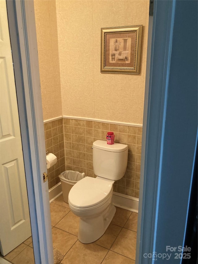 bathroom with tile patterned floors, toilet, and tile walls