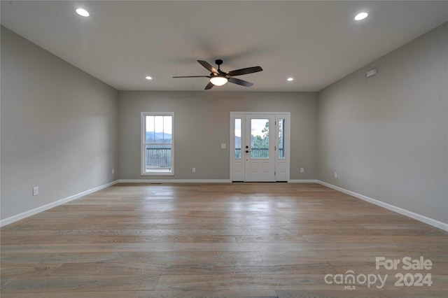 empty room with ceiling fan, a healthy amount of sunlight, and light hardwood / wood-style flooring