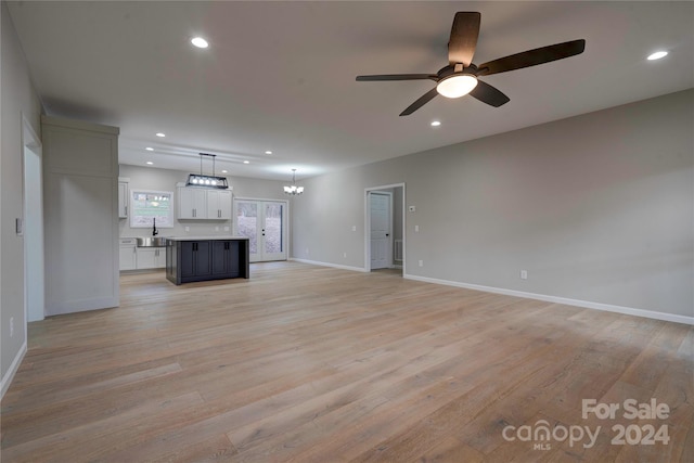 unfurnished living room with french doors, light hardwood / wood-style floors, ceiling fan, and sink