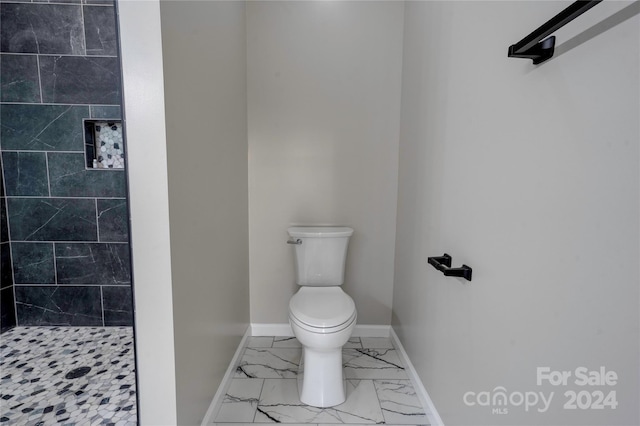 bathroom with a tile shower and toilet