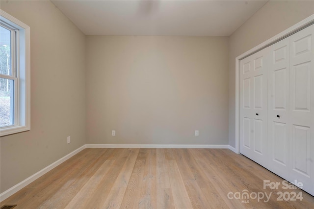 unfurnished bedroom with a closet and light hardwood / wood-style floors