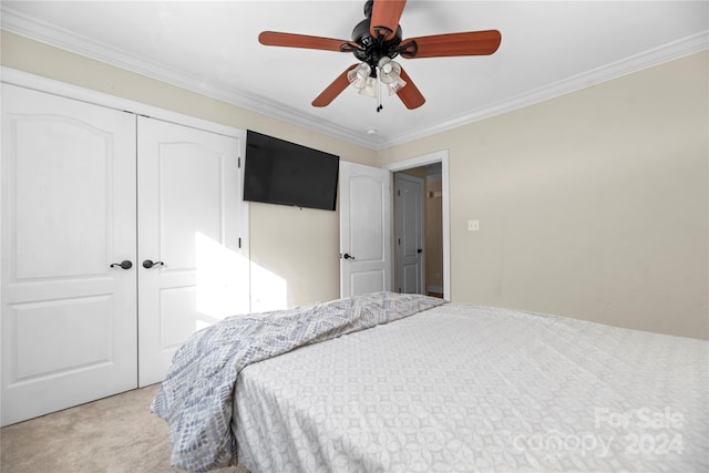 bedroom featuring ceiling fan, crown molding, light carpet, and a closet