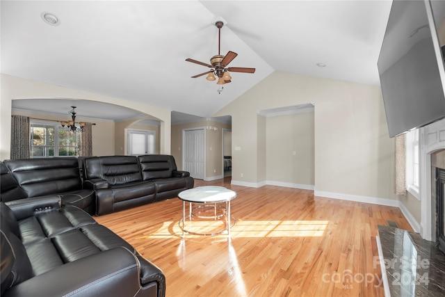 living room with lofted ceiling, a fireplace, ceiling fan with notable chandelier, and light wood-type flooring