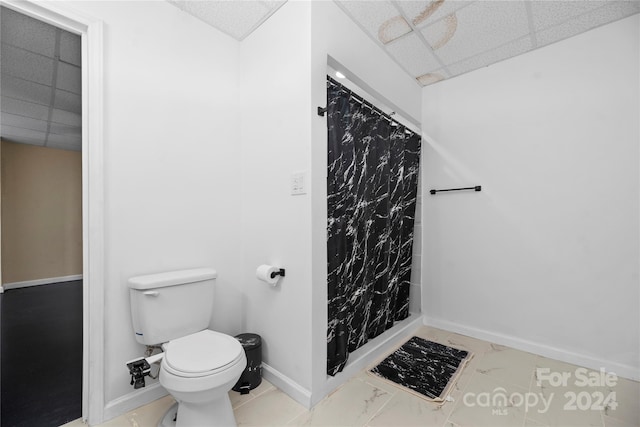 bathroom with walk in shower, a paneled ceiling, and toilet