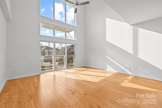 unfurnished living room with a high ceiling, light hardwood / wood-style flooring, and ceiling fan