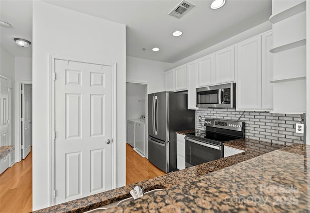 kitchen with washing machine and clothes dryer, backsplash, white cabinetry, and stainless steel appliances