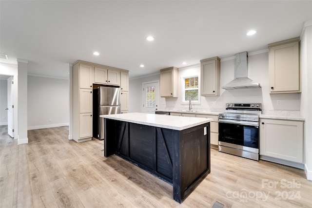 kitchen with crown molding, light hardwood / wood-style flooring, wall chimney exhaust hood, and appliances with stainless steel finishes