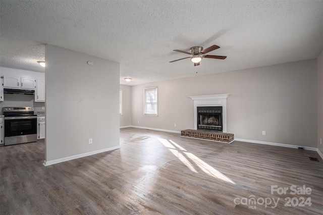 unfurnished living room with a textured ceiling, a brick fireplace, and dark wood-type flooring